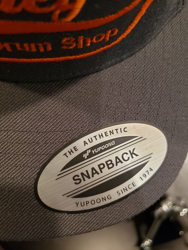 Gorra de tela con cierre trasero tipo snapback de Bentley's Drum Shop en gris y logotipo naranja